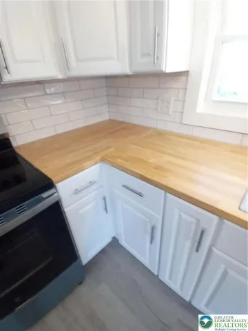 a view of a kitchen with white cabinets and a stove top oven