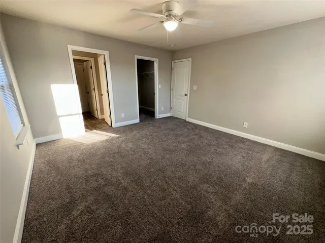 an empty room with closet and a ceiling fan