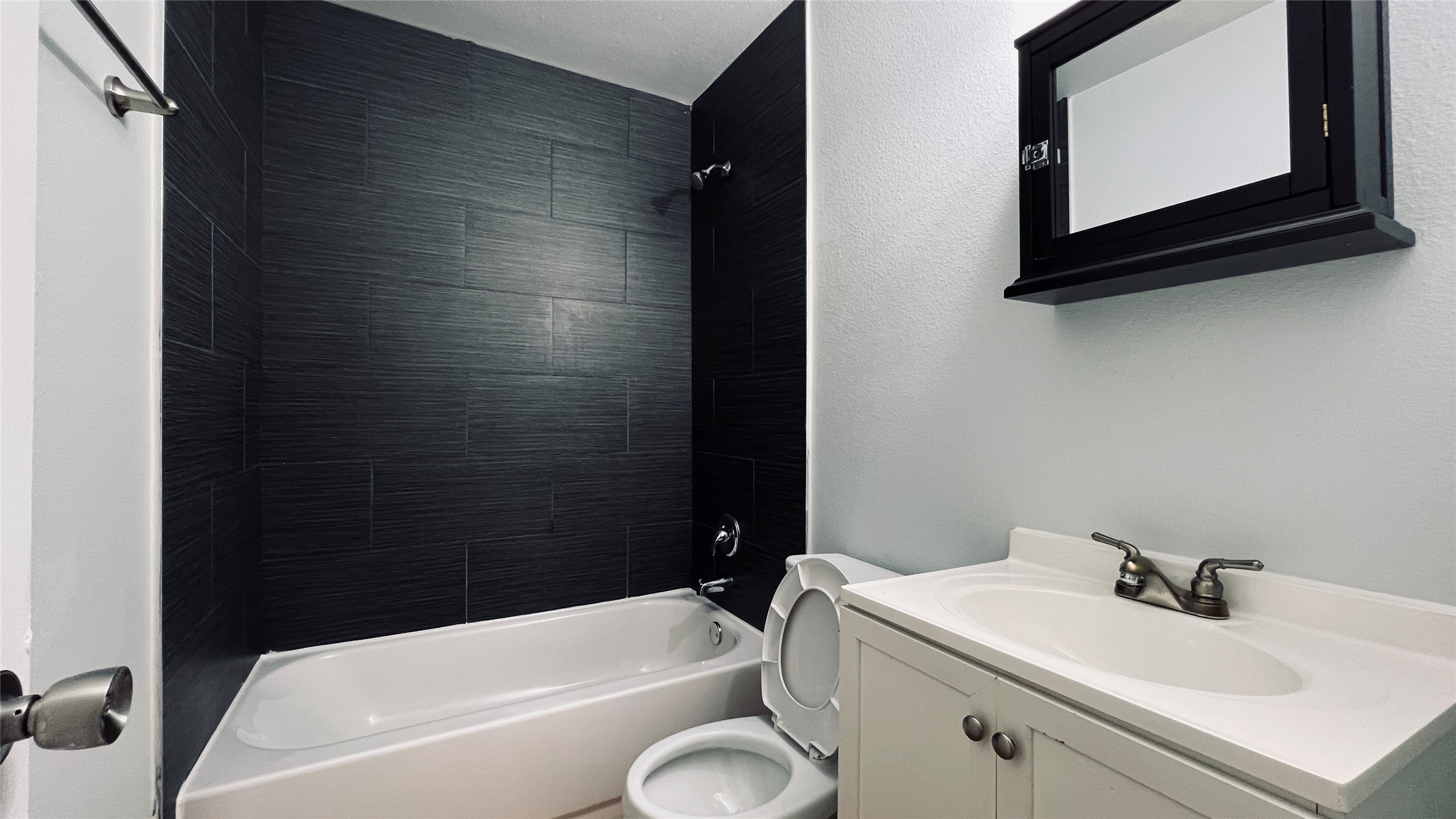 2301 Ohlen Road, Unit 209 Austin, TX 78757 - Photo 9 of 10 A well-appointed bathroom features a crisp white vanity and a chic dark-tiled shower-tub combination.