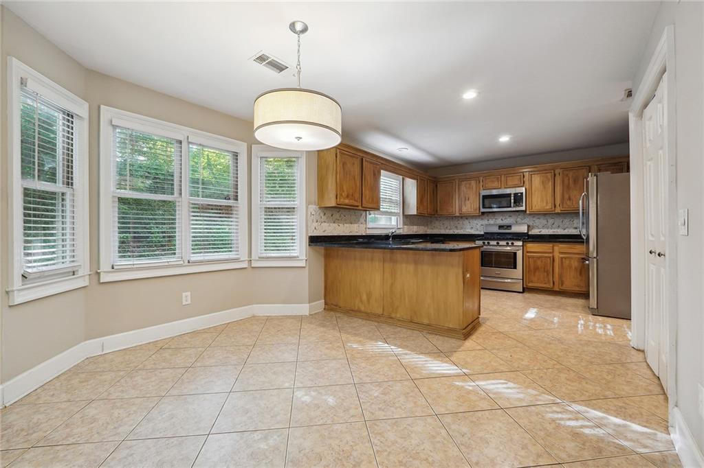 515 Spring Gate Lane Alpharetta, GA 30009 - Photo 13 of 36 a large kitchen with stainless steel appliances granite countertop a stove top oven a sink dishwasher a dining table and chairs in the kitchen