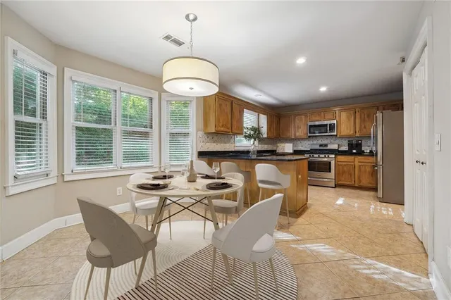 a kitchen with stainless steel appliances kitchen island granite countertop a stove a sink a dining table and chairs