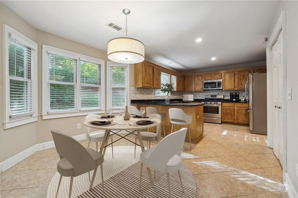 515 Spring Gate Lane Alpharetta, GA 30009 - Photo 3 of 36 a kitchen with stainless steel appliances kitchen island granite countertop a stove a sink a dining table and chairs