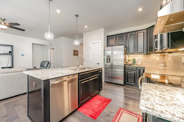 a kitchen with stainless steel appliances granite countertop a sink a stove and a refrigerator