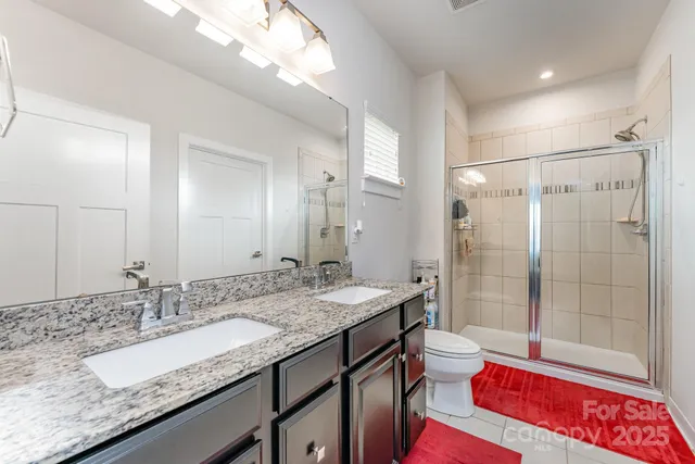 a bathroom with a granite countertop sink a toilet and shower