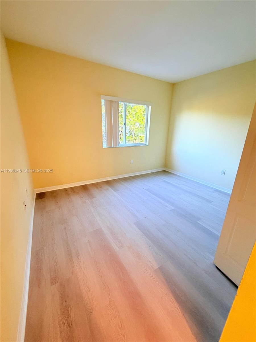 12635 Southwest 91st Street, Unit 211 Miami, FL 33186 - Photo 4 of 16 a view of an empty room with wooden floor and a window
