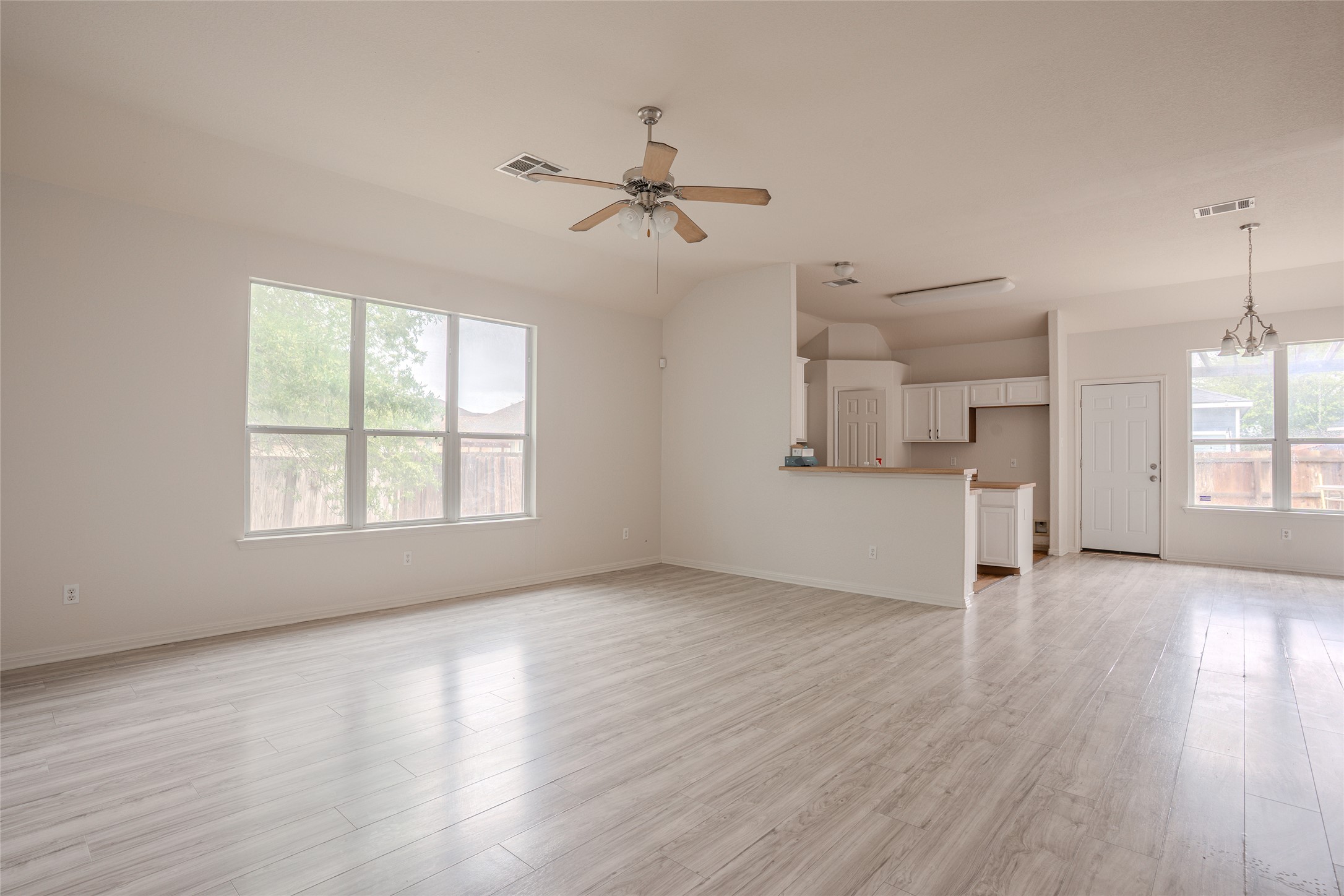 140 Dropper Kyle, TX 78640 - Photo 12 of 30 an empty room with wooden floor a ceiling fan and windows