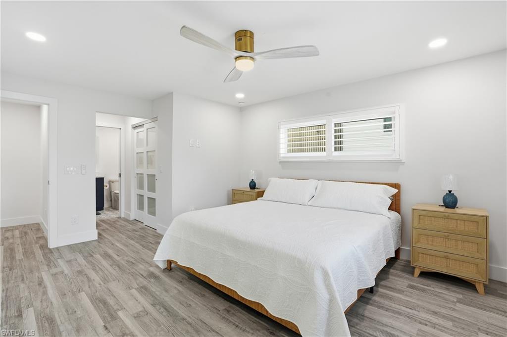 270 Dundee Road Fort Myers Beach, FL 33931 - Photo 19 of 48 Bedroom featuring ceiling fan, connected bathroom, light wood-style flooring, and recessed lighting - Virtually Edited Image
