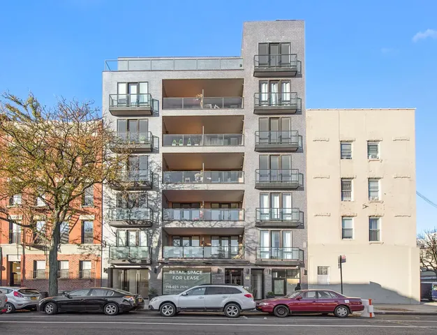 a front view of a building with lot of cars and trees