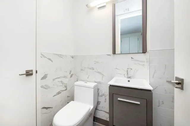 a bathroom with a toilet sink vanity and mirror