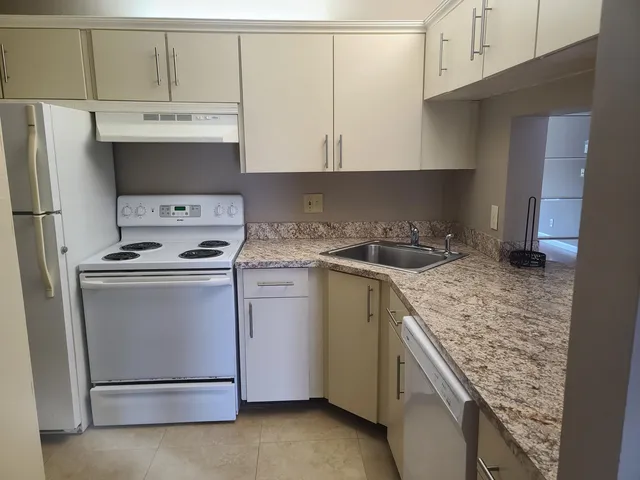 a kitchen with granite countertop a sink stove and refrigerator