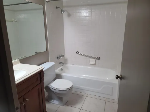 a bathroom with a granite countertop bathtub shower sink vanity and toilet