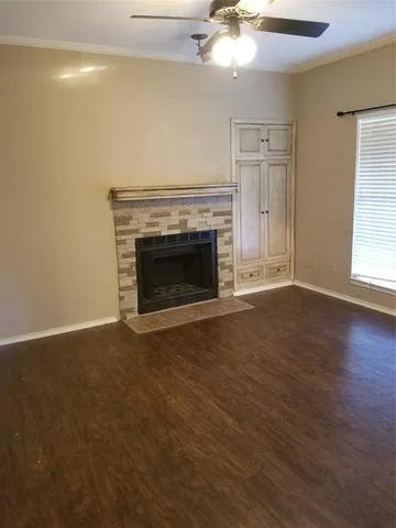 an empty room with wooden floor fireplace and windows