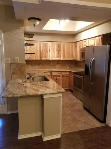 a kitchen with stainless steel appliances granite countertop a sink and a refrigerator