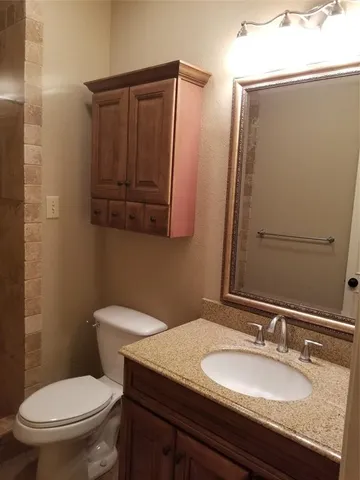 a bathroom with a granite countertop toilet sink and mirror