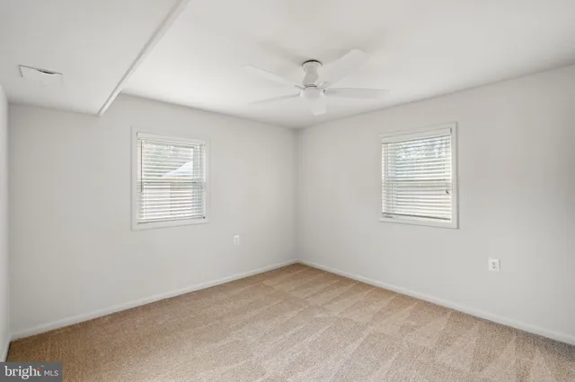 an empty room with a window and ceiling fan