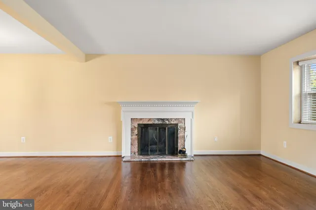 a view of an empty room with wooden floor and a fireplace