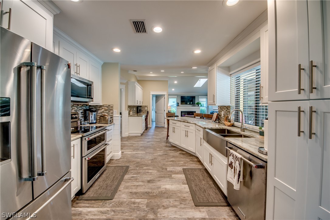 a kitchen with stainless steel appliances kitchen island granite countertop a stove top oven a sink and a refrigerator