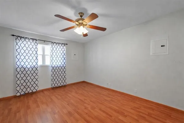 an empty room with wooden floor fan and windows