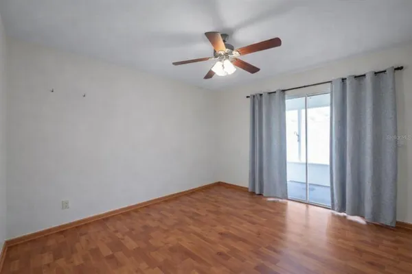 a view of empty room with wooden floor and fan