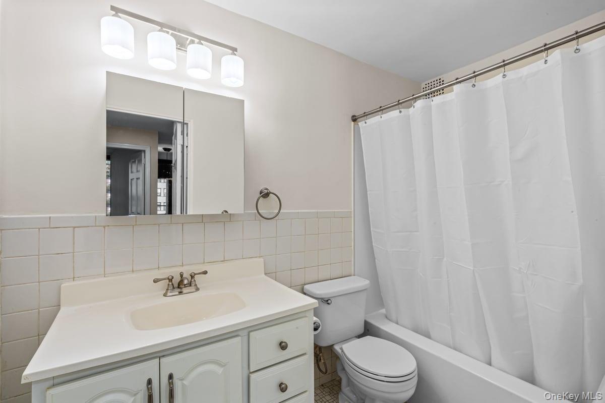168-11 12th Avenue, Unit 3D Queens, NY 11357 - Photo 15 of 21 a bathroom with a sink a toilet and shower curtain