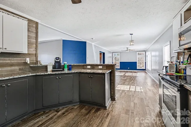 a kitchen with stainless steel appliances granite countertop a stove top oven a sink dishwasher a dining table and chairs with wooden floor