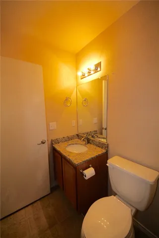 a bathroom with a granite countertop toilet sink and mirror