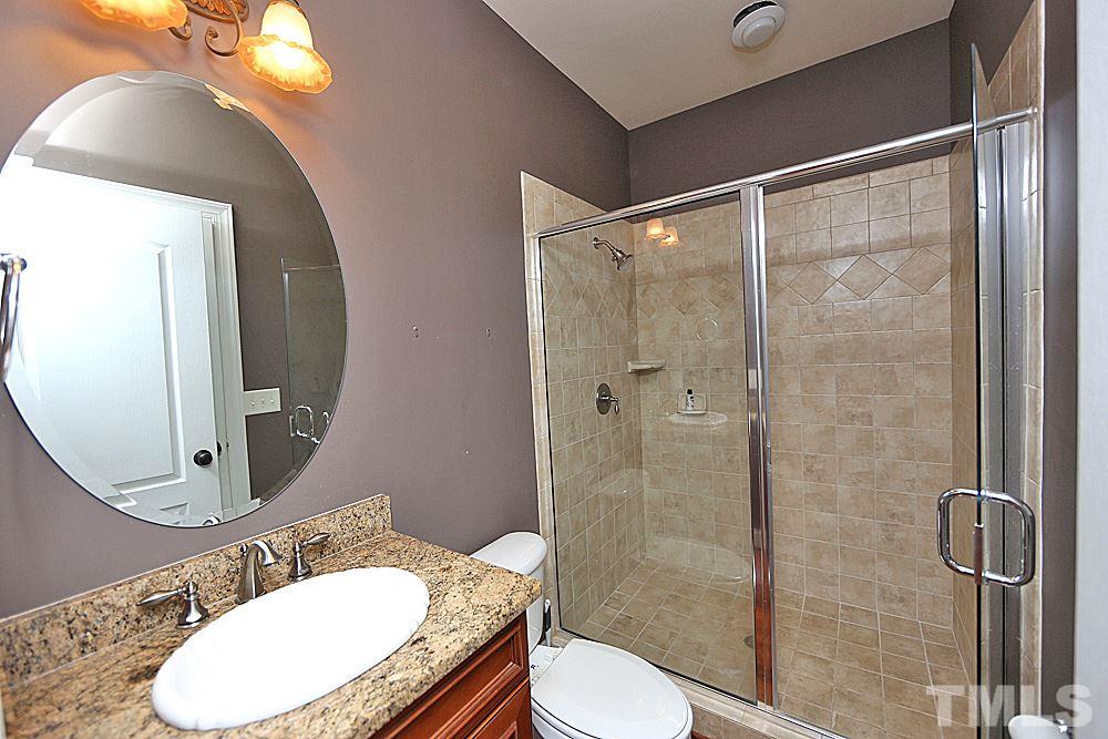 5214 Landguard Drive Raleigh, NC 27613 - Photo 11 of 20 a bathroom with a granite countertop toilet a sink and shower