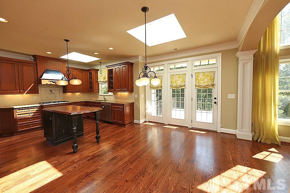 5214 Landguard Drive Raleigh, NC 27613 - Photo 6 of 20 a open kitchen with stainless steel appliances granite countertop a stove a refrigerator a sink a dining table and chairs with wooden floor
