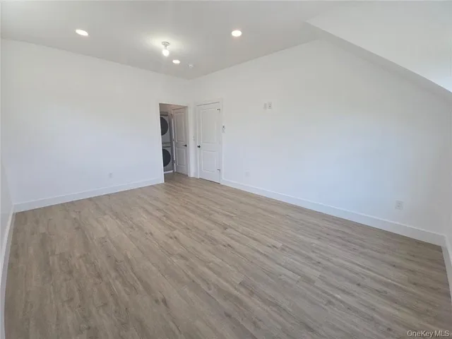 an empty room with wooden floor mirror and windows