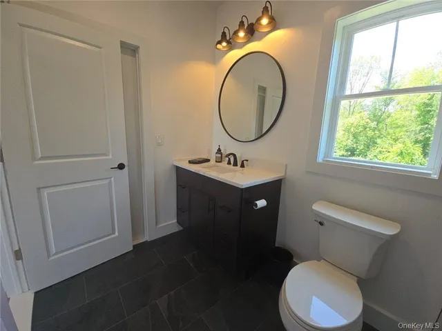 a bathroom with a toilet sink vanity granite and a mirror