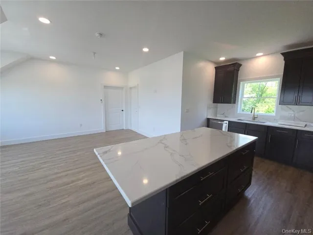 a view of kitchen island a sink wooden floor and a living room