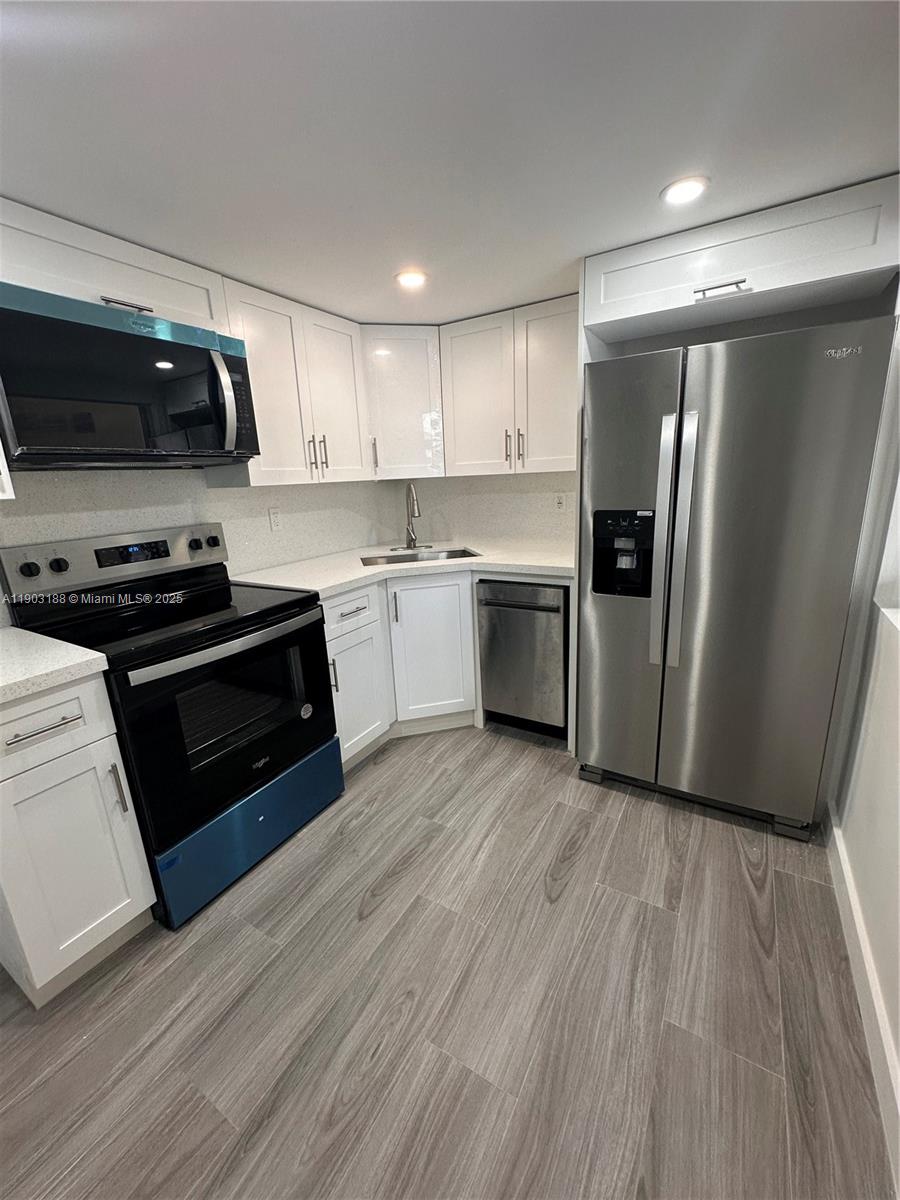 7705 Southwest 86th Street, Unit B315 Miami, FL 33143 - Photo 1 of 28 a kitchen with stainless steel appliances granite countertop a refrigerator a stove top oven a sink and dishwasher with wooden floor