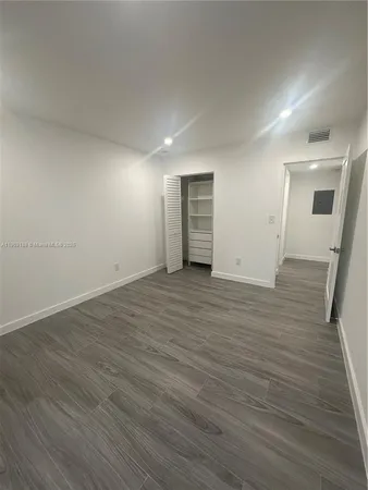 an empty room with wooden floor and mirror