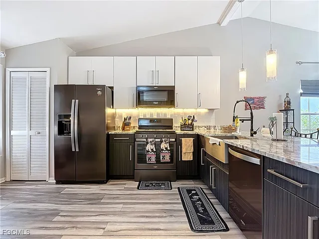 a kitchen with granite countertop a refrigerator stove and sink