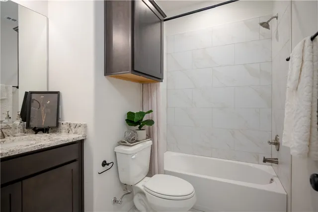 a bathroom with a granite countertop sink a toilet and bathtub