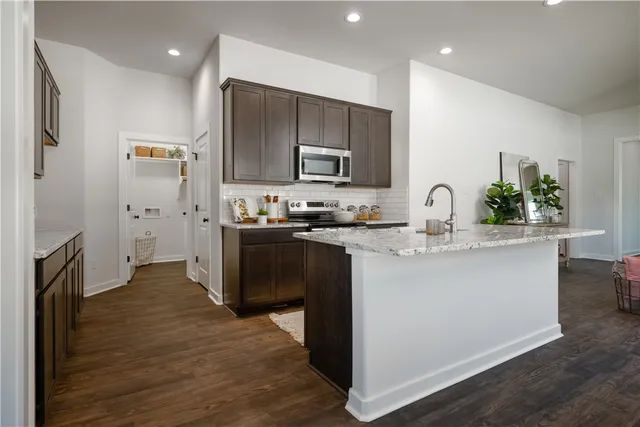 a kitchen with kitchen island granite countertop a refrigerator oven a sink and dishwasher with wooden floor