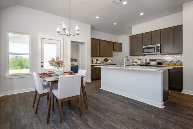 a kitchen with a dining table chairs and refrigerator