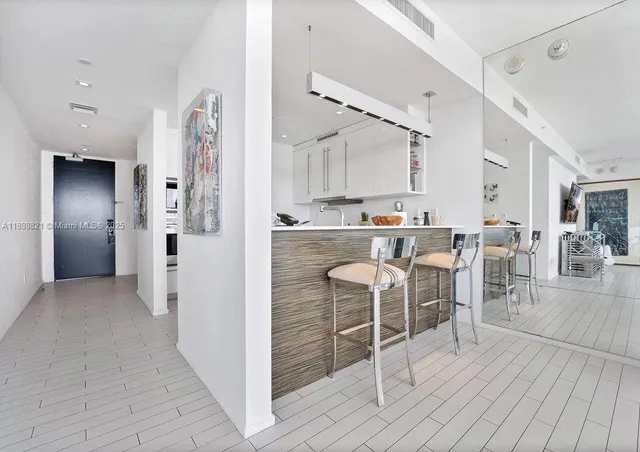 a kitchen with stainless steel appliances kitchen island granite countertop dining table chairs and cabinets