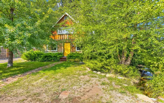 a view of a brick house with large windows and a yard with plants