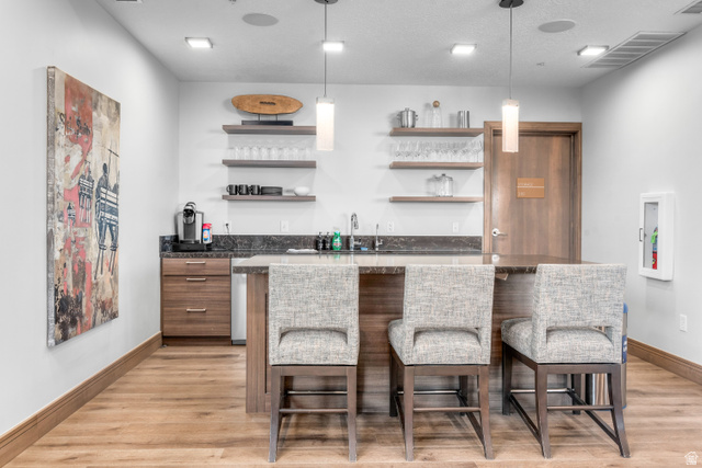 1258 Rothwell Road Park City, UT 84060 - Photo 45 of 48 Wet bar featuring wood-finish flooring, dark stone countertops, wood cabinetry, and open shelving