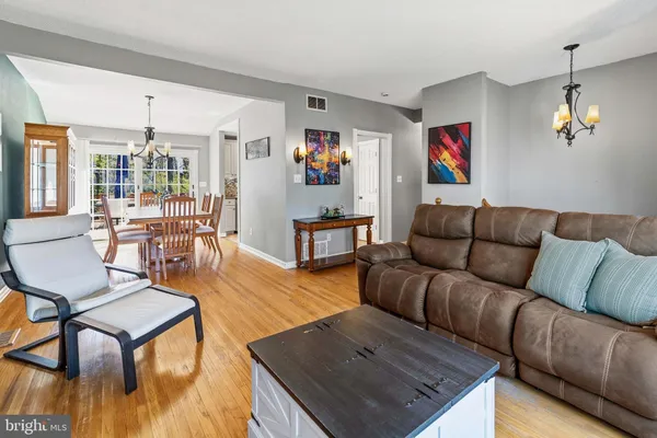 a living room with furniture kitchen view and a wooden floor