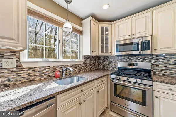 a kitchen with granite countertop a sink stainless steel appliances and cabinets