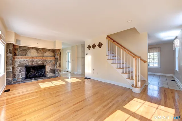 a view of an empty room with wooden floor fireplace and a window