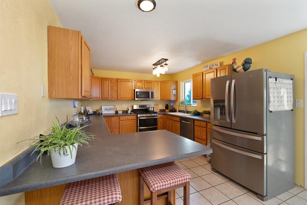 3641 Catlett Road Pleasant Grove, CA 95668 - Photo 3 of 29 a kitchen with granite countertop stainless steel appliances a stove a sink a microwave a dining table and chairs