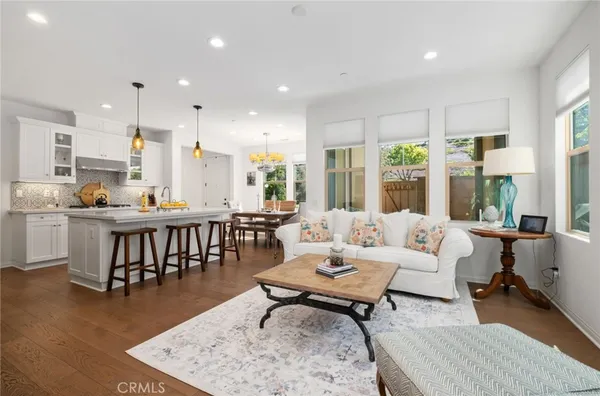 a living room with stainless steel appliances furniture a rug kitchen view and a large window