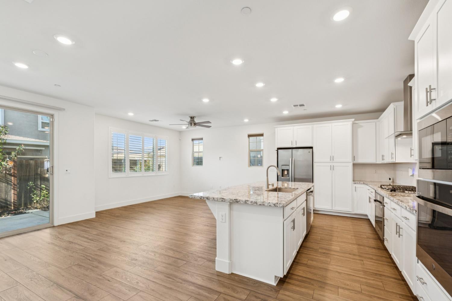 10458 Oboe Way Elk Grove, CA 95757 - Photo 5 of 38 a large kitchen with stainless steel appliances kitchen island granite countertop a large counter top and a stove top oven