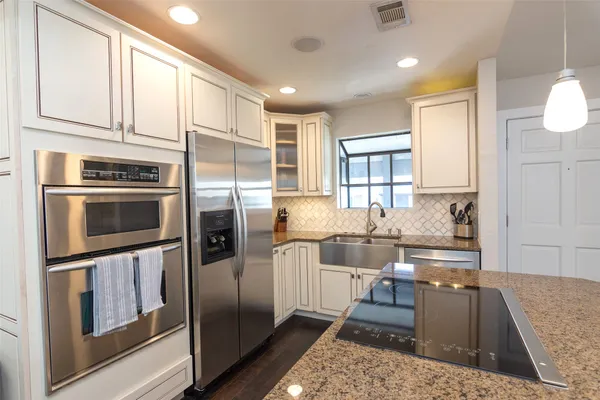 a kitchen with stainless steel appliances granite countertop a refrigerator and a stove top oven