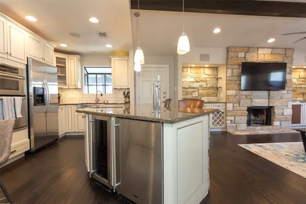a kitchen with stainless steel appliances granite countertop a refrigerator a sink a stove and a microwave