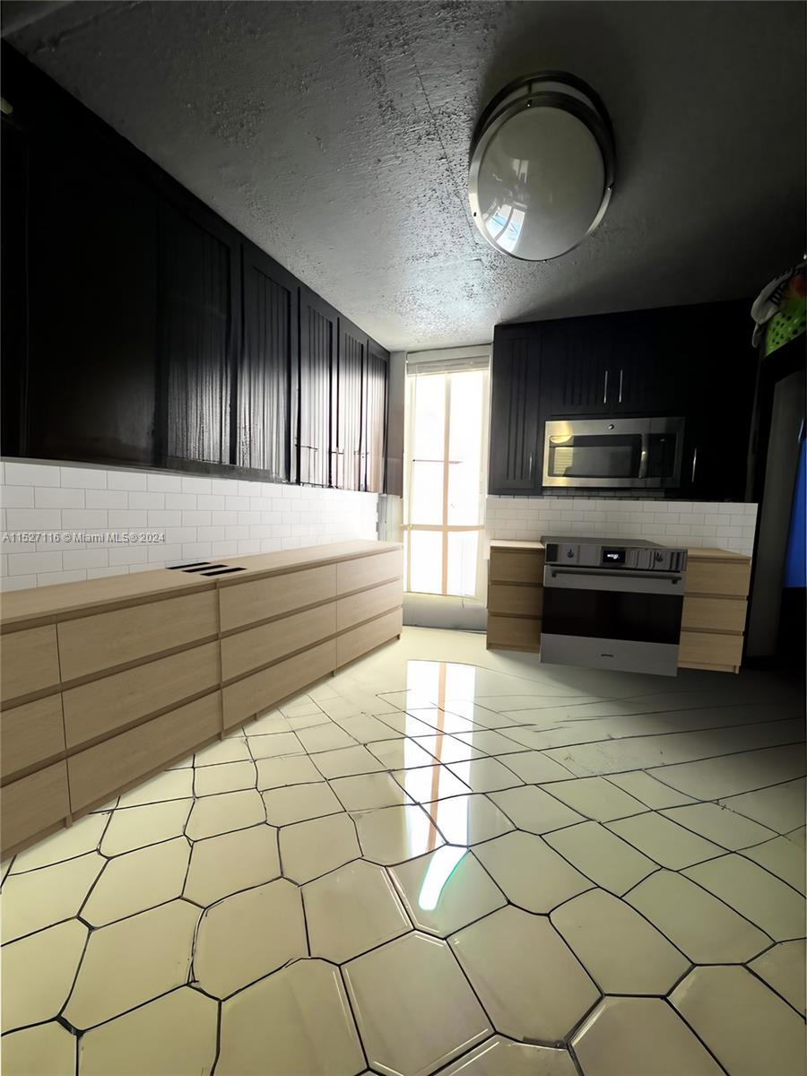 1665 Bay Road, Unit 425 Miami Beach, FL 33139 - Photo 25 of 29 a kitchen with stainless steel appliances a stove a sink and a microwave