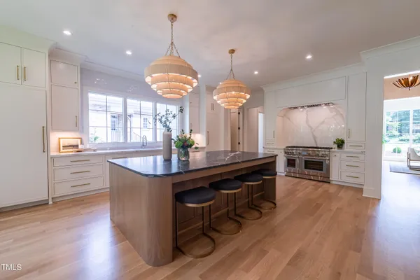 a kitchen with stainless steel appliances kitchen island granite countertop a table chairs and a refrigerator